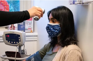 Dark haired student with mask getting her temperature taken