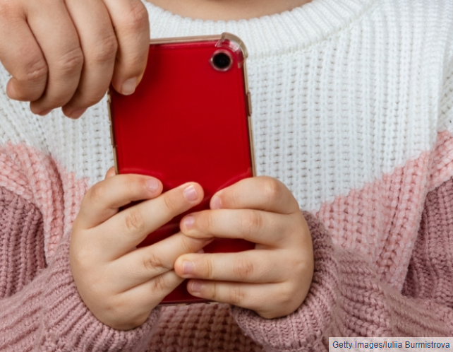 Adult hand removing cell phone from hands of a young child