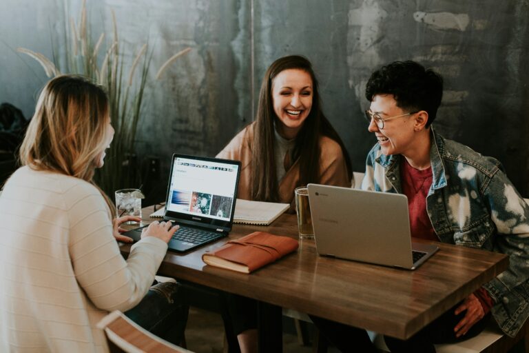 Three women sitting around a table with laptops