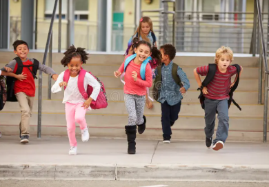 Happy children running down the steps of a school building.