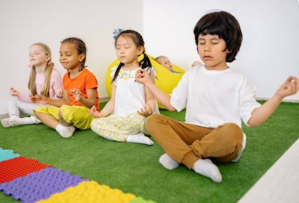 Four children sitting on mats in a mindfulness pose