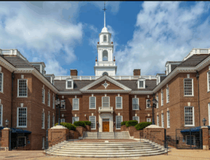 A red brick building with red front door and a steeple in the middle where Delaware lawmakers meet.