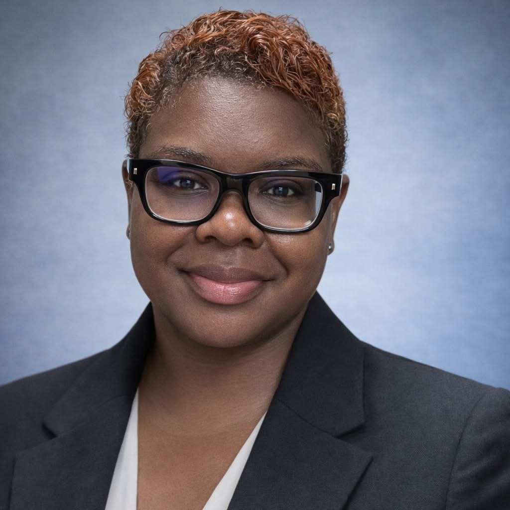 Black woman with short hair and wearing glasses looking at the camera