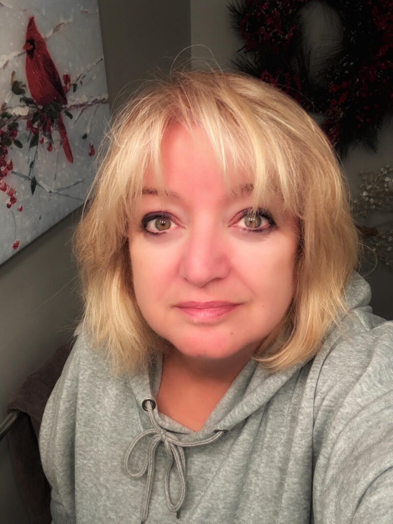 White woman with blond hair and bands looking at camera