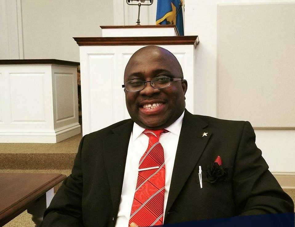 Smiling Black man with glasses and wearing a business suit, smiling at the camera