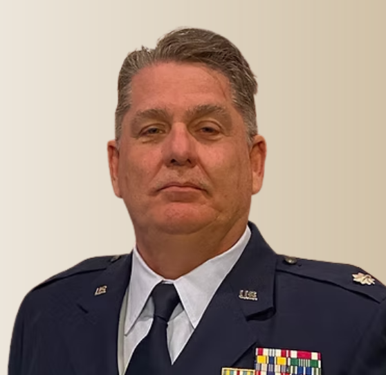 Middle-aged man in a military uniform with ribbons looking directly into the camera