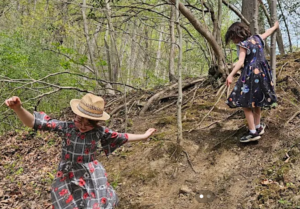 Two girls in dresses running down the side of a steep hill