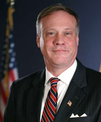 A man dressed in a suit looking straight at the camera with a slight smile